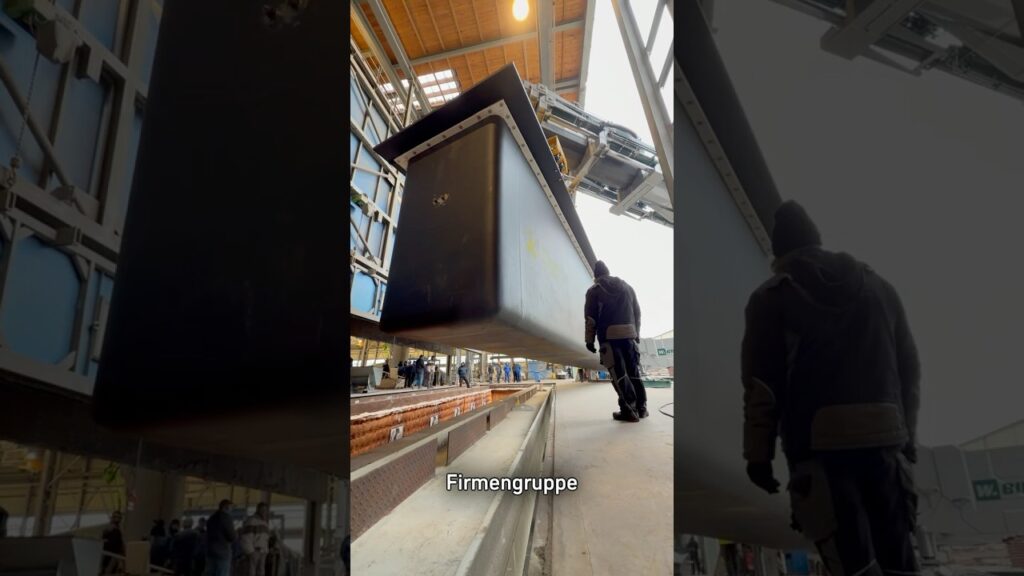 Ein Zinkkessel hängt am Hallenkran über der Verzinkungsanlage, darunter ein Mitarbeiter – Standbild aus dem Reel zum Zinkkesselwechsel bei WIEGEL