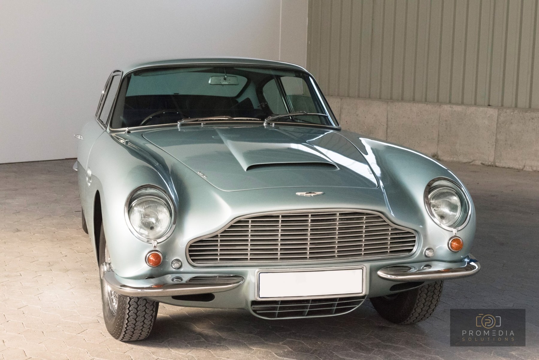 Silberner Aston Martin DB6 von vorn in einer Werkhalle